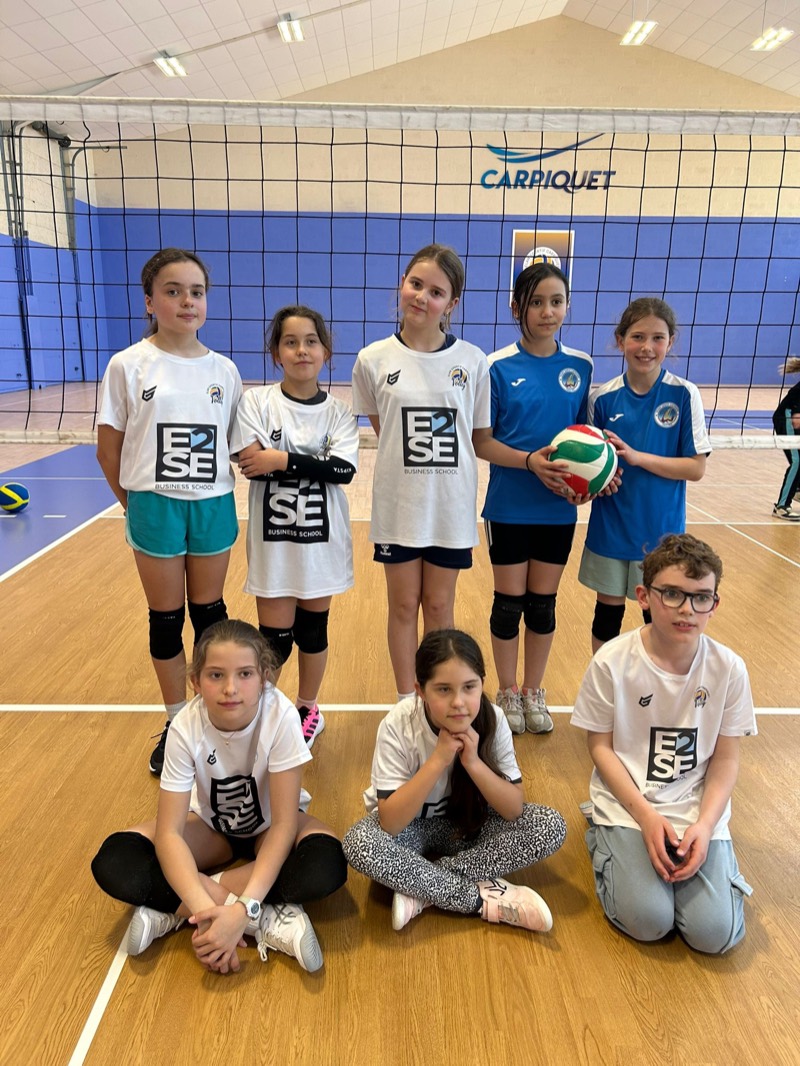 Groupe de jeunes joueurs en maillots blancs et bleus, un ballon à la main, dans un gymnase