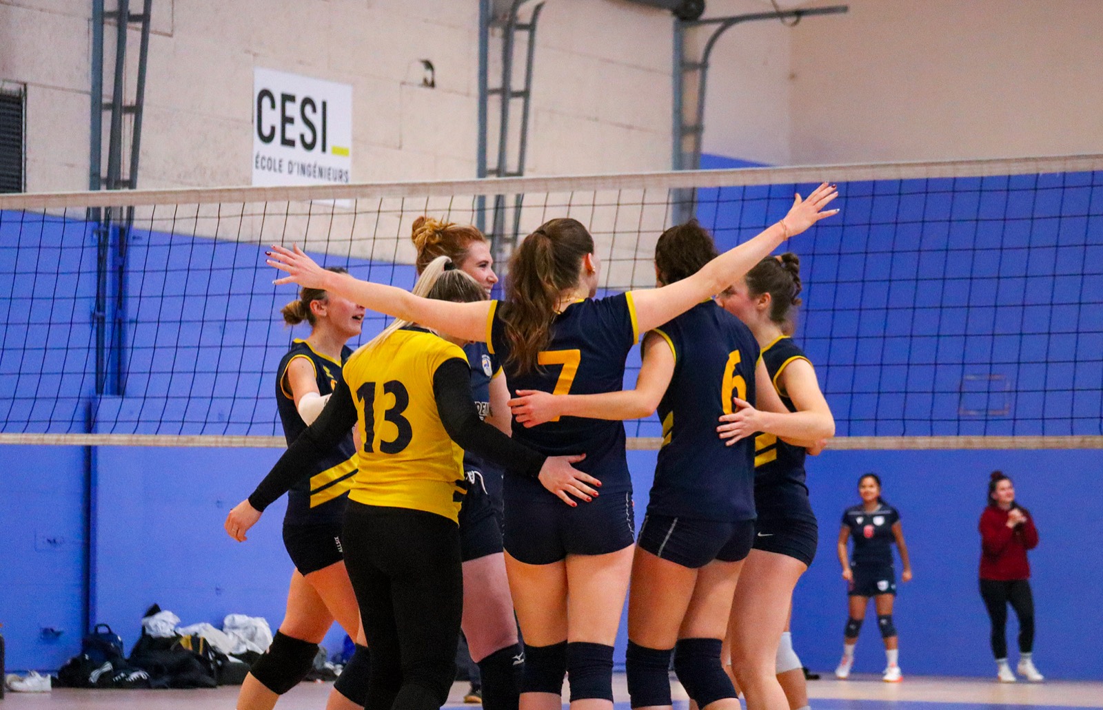 Joueuses en maillots bleu nuit et jaune qui se félicitent au filet